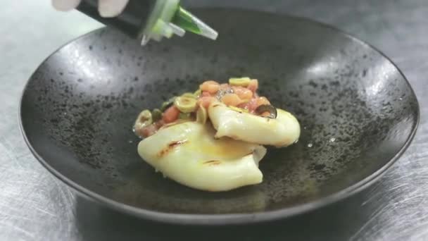 Chef professionista in cucina prepara calamari in salsa. lo chef decora il piatto su un piatto con erbe verdi. Delizioso pranzo gourmet preparato nella cucina di casa — Video Stock