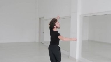 Genç yakışıklı adam balo dansı yapıyor. Profesyonel bir balo dansçısı büyük beyaz bir salonda antrenman yapar..