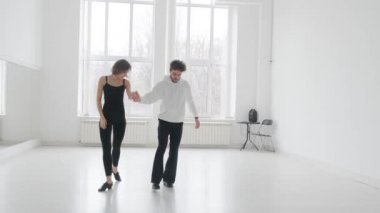 Genç ve güzel bir çift balo dansı eğitimi alıyor. Profesyonel bir balo dansı çifti büyük, parlak, beyaz bir salonda dans eder.