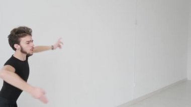 Genç yakışıklı adam balo dansı yapıyor. Profesyonel bir balo dansçısı büyük beyaz bir salonda antrenman yapar..