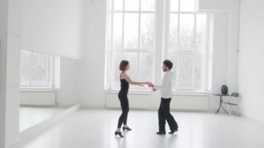 Genç ve güzel bir çift balo dansı eğitimi alıyor. Profesyonel bir balo dansı çifti büyük, parlak, beyaz bir salonda dans eder.
