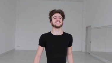 Genç yakışıklı adam balo dansı yapıyor. Profesyonel bir balo dansçısı büyük beyaz bir salonda antrenman yapar..