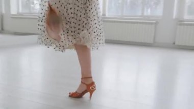 Çekici kız, parlak beyaz bir salonda aynanın önünde dans ediyor. Profesyonel bir balo dansçısı koreografi salonunda antrenman yapar..