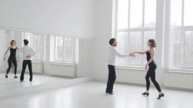 Genç ve güzel bir çift balo dansı eğitimi alıyor. Profesyonel bir balo dansı çifti büyük, parlak, beyaz bir salonda dans eder.