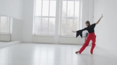 Çekici kız, parlak beyaz bir salonda aynanın önünde dans ediyor. Profesyonel bir balo dansçısı koreografi salonunda antrenman yapar..