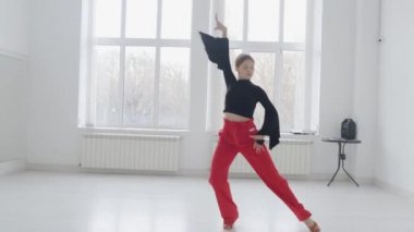 Çekici kız, parlak beyaz bir salonda aynanın önünde dans ediyor. Profesyonel bir balo dansçısı koreografi salonunda antrenman yapar..