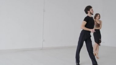 Genç ve güzel bir çift balo dansı eğitimi alıyor. Profesyonel bir balo dansı çifti büyük, parlak, beyaz bir salonda dans eder.