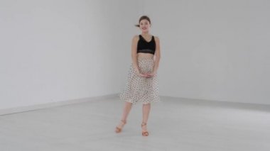 Çekici kız, parlak beyaz bir salonda aynanın önünde dans ediyor. Profesyonel bir balo dansçısı koreografi salonunda antrenman yapar..