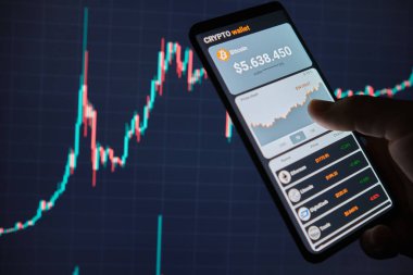 Mobil uygulama şifreleme cüzdanlı akıllı telefon. Bir adam bitcoin 'in fiyat tablosunu mobil bir uygulamada analiz eder. Kripto para ticareti kavramı 