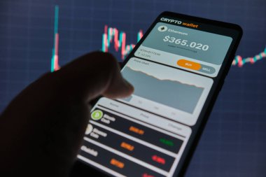 Mobil uygulama şifreleme cüzdanlı akıllı telefon. Bir adam mobil bir uygulamada ethereum 'un fiyat tablosunu analiz eder. Kripto para ticareti kavramı 