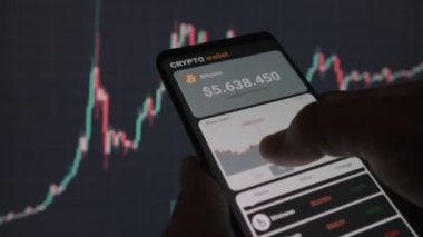 A man analyzes the price chart for bitcoin in a mobile application. Smartphone with mobile application cryptocurrency wallet. The concept of cryptocurrency trading 
