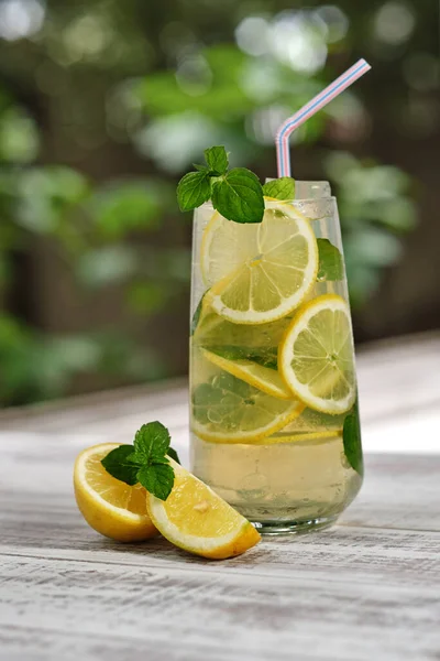 Bardakta soğuk limonata ve ahşap bir masada meyve. Yaz için tropik ferahlatıcı soğuk içecek. Limon ve nane ile detoksifikasyon için soğuk su 