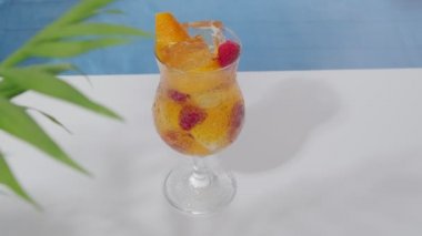 Havuzun yanında ahududu ve buz dolu parlak turuncu kokteyl. Tazeleyici içecek. Sıcak bir yaz gününde hafif içkiler. Yazın plaj partisi.