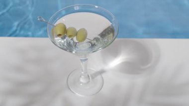 Havuz kenarında martini ve zeytinli kokteyl bardağı. Sıcak bir yaz gününde hafif içkiler. Yazın plaj partisi.