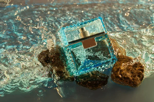 Parfüm, kozmetik marka konsepti - parfüm şişesi denizde duruyor ve deniz dalgaları tarafından yıkanan taşlar. Eau de parfum, lüks güzellik markası.