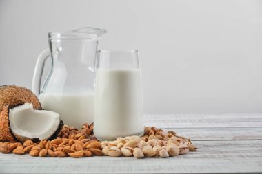 Bardakta sebze sütü ve tahta bir arka planda sürahi. Farklı malzemelerden sebze sütü: Hindistan cevizi, fındık, kaju, fıstık, badem. Sağlıklı Yeme 