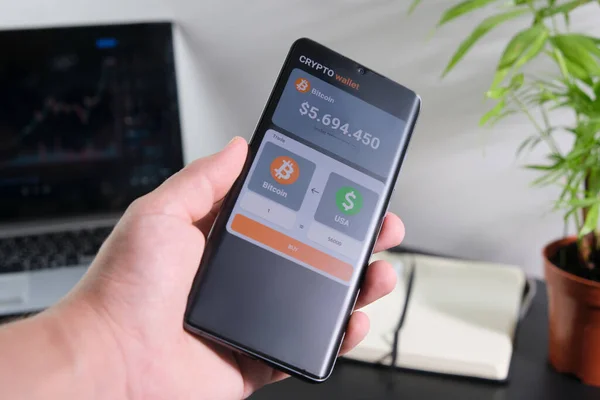 Bir adam mobil bir uygulama üzerinden bitcoin satın alır. Mobil uygulama şifreleme cüzdanlı akıllı telefon. Kripto para ticareti kavramı