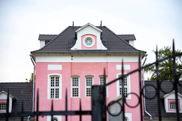 Oud Roze Huis Achter Zwarte Balken Tegen Een Bewolkte Lucht — Stockfoto