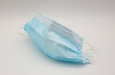 Biri beyaz arka planda tıbbi koruyucu maske kullanmış..