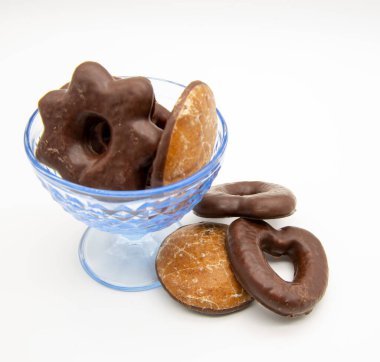 Beyaz arka planda, farklı boyutlarda ve şekillerde zencefilli kek içeren mavi cam bir vazo..