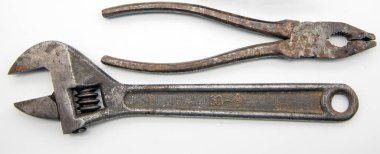 Paslı pense ve beyaz arka planda ayarlanabilir İngiliz anahtarı..