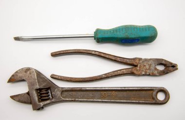 Beyaz arka planda eski el aletleri, tornavida, anahtar ve pense seti.