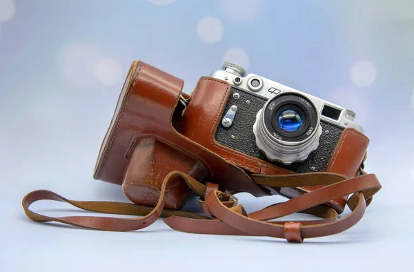 An old-fashioned camera with a leather case on a blue elegant background.