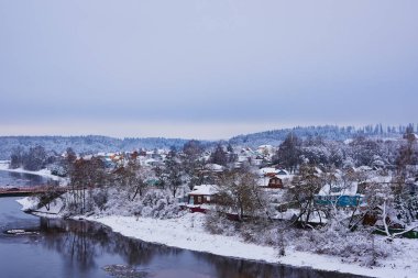 Kış kırsal arazisi. Nehir kıyısında karla kaplı bir köy..