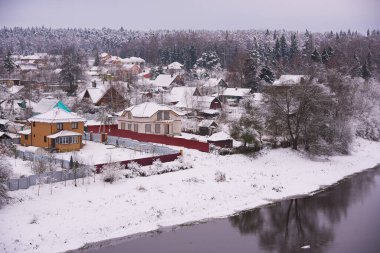 Nehrin kıyısında renkli ahşap evleri olan karla kaplı bir köy..