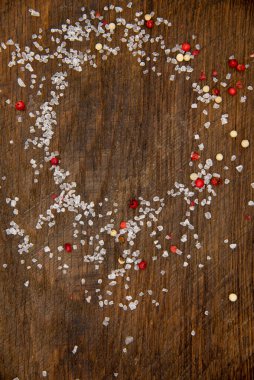 Tuz ve biber serpiştirilmiş bir kesim tahtasının üst görüntüsü. Baharatlar bir daire oluşturuyor. Paketleme için arkaplan.