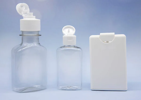 Garrafas cosméticas vazias transparentes e frascos em um fundo azul. — Fotografia de Stock