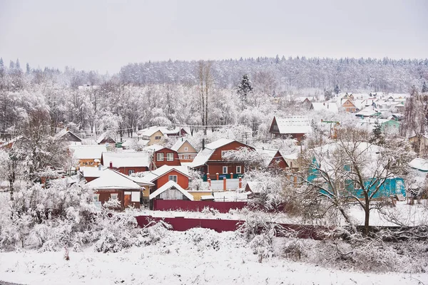 Hófödte Falu Világos Faházakkal Erdő Hátterében Felhős Égbolttal — Stock Fotó