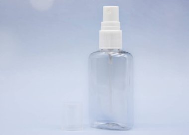 Yumuşak mavi arka planda şeffaf boş kozmetik şişeleri ve kavanozlar.