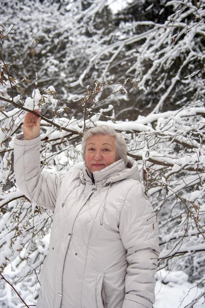 在冬天的雪地里散步时 一位白发苍苍的老妇人穿着一件轻薄的夹克 — 图库照片
