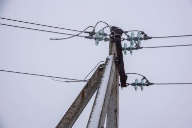 Bir kış günü bulutlu bir gökyüzünün arka planına karla kaplı elektrik hattı..