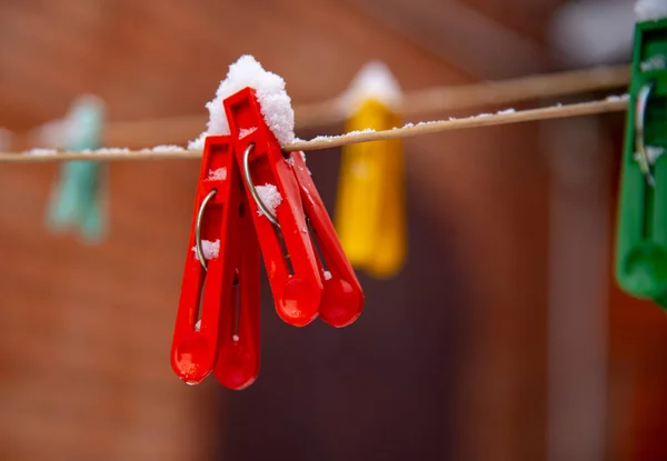 Brillanti mollette ricoperte di neve su una clothesline. — Foto Stock