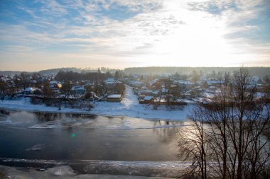 Donmuş nehir, kıyıda karla kaplı köy..