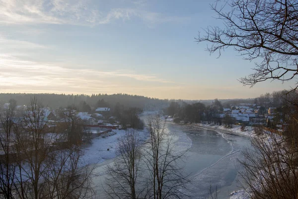 Donmuş nehir, kıyıda karla kaplı köy..