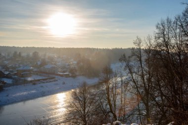 Donmuş nehir, kıyıda karla kaplı köy..