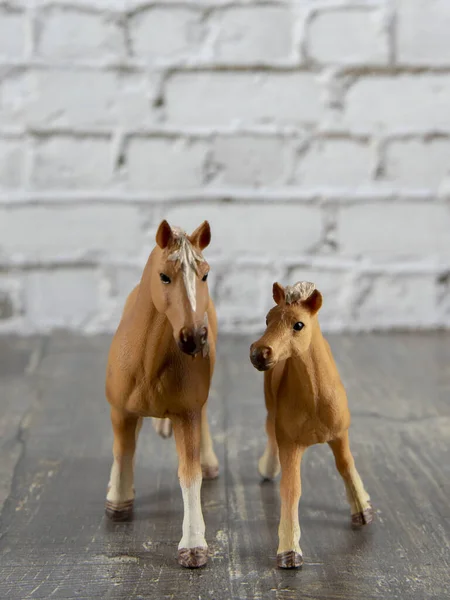 İki kahverengi oyuncak at, açık tuğlalı bir duvara karşı.. — Stok fotoğraf