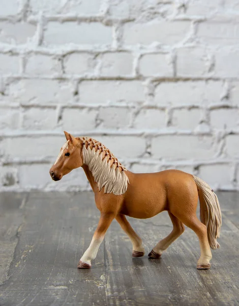 Un caballo marrón juguete contra una pared de ladrillo. — Foto de Stock
