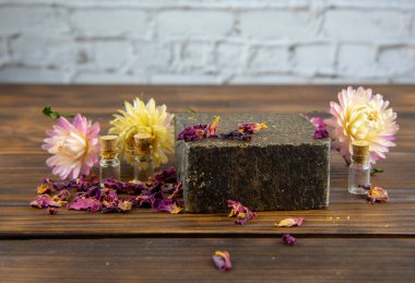 Kurumuş çiçeklerle süslenmiş el yapımı sabun fırçası kahverengi ahşap tezgahta yatıyor. Sağlıklı yaşam tarzı kavramı.