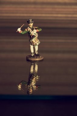 Bir teneke asker cam yüzeyde duruyor, yansıtıyor..