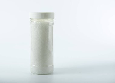 Açık arkaplanda kaba tuz bulunan şeffaf kavanoz..