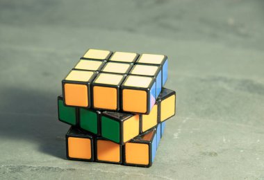 Gri arka planda parlak bir bulmaca. Parçalanmış halde Rubik Küpü.