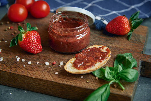 Домашняя ягода и томатный соус в стеклянной банке.