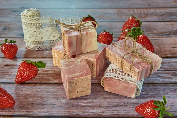Jabón texturizado rosa hecho a mano, encaje y fresas sobre un fondo de madera. — Foto de Stock