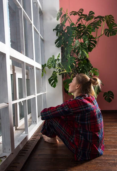 Een tienermeisje in pyjama zit voor een panoramisch raam . — Stockfoto