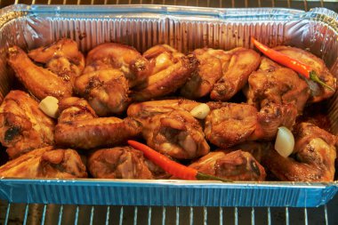 Salamuradaki tavuk kanatları fırında alüminyum bir formda pişirilir..