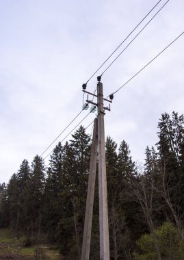Bulutlu bir gökyüzüne karşı yüksek voltajlı bir güç hattı. Güç hattı sütunları.